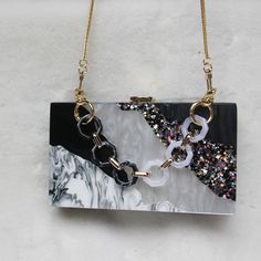 Editor's Notes: A delicate combination of tones. A rectangular clutch with a geometrical pattern. The surface has a raw water-like texture and a resin-like look. This clutch is sure to grab attention. There is enough room for all your essentials. The clutch comes with two chains: a short one to carry the clutch as a handbag and a long one to carry the clutch on the shoulder. Size 7 x 4.3 x 2 inches (18 x 11 x 5 cm) Material PVC, polyester, and acrylic Details Removable chain shoulder strap Clasp Modern Clutch Evening Bag, Elegant Rectangular Clutch With Chain, Formal Rectangular Clutch With Chain, Elegant Rectangular Chain Clutch, Rectangular Clutch With Chain For Gift, Gift Clutch With Chain Detail, Trendy Clutch With Chain Strap For Gift, Trendy Clutch With Chain Strap As A Gift, White Rectangular Clutch With Chain Strap