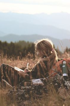 a woman sitting in front of a campfire and looking at the moon