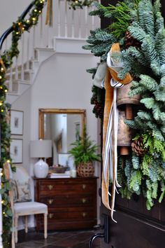 a christmas wreath hanging on the front door of a house with stairs in the background