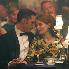 a man and woman sitting next to each other at a table with wine glasses in front of them