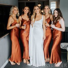 the bridesmaids are holding champagne flutes and posing for a photo in their dresses