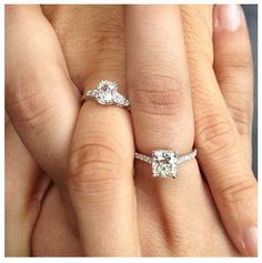 two women's hands with wedding rings and engagement bands on their fingers, one has an oval shaped diamond in the center