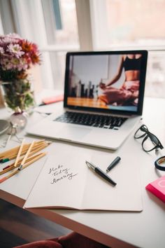 an open laptop computer sitting on top of a desk next to a notepad and pen