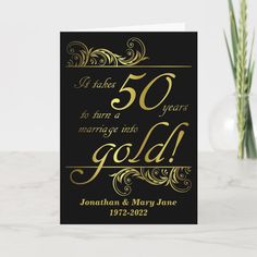 a 50th anniversary card with the words 50 years marriage into gold on it, next to a vase filled with flowers