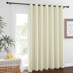 a white curtain hanging in front of a window next to a table with fruit on it