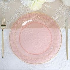 a pink plate and silverware on a lace tablecloth with white flowers in the background