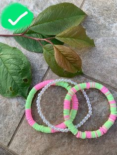 three bracelets sitting on top of a stone floor next to a green leaf