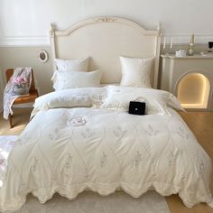 a bed with white comforter and pillows in a room