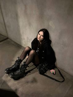 a woman is sitting on the floor with her legs crossed and wearing black leather boots