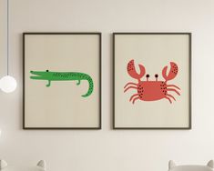 two framed pictures with animals on them in a room next to each other, one has a green alligator and the other is a red crab