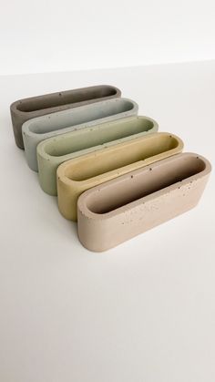 four different colored clay containers sitting on top of a white table