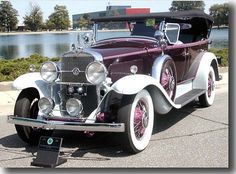 an antique car is parked in front of the water