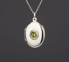 An oval sterling silver photo locket necklace with an oval bezeled mother of pearl on the front: 1. an elegant oval solid sterling silver locket (27 x 22 mm, 5 mm thick, 6.4 grams) that can hold two pictures inside.     It has an exquisite oval peridot ( ~ 7 x 5 mm) set on decorative bezel (11 x 9 mm) on the front.     Its back can be engraved with text, simple line-drawing graphics, a fingerprint or a handwriting (please use pulldown menu to select)      2.  Photo insertion service can be selec White Oval Pendant With Polished Finish, White Gold Sterling Silver Oval Pendant Locket Necklace, Elegant Birthstone Medallion Locket Necklace, Elegant Silver Locket Necklace With Birthstone, White Locket Necklace For Memorial, Oval White Gold Locket Necklace For Keepsake, White Gold Oval Locket Necklace For Keepsake, Oval White Gold Locket Necklace Keepsake, White Engraved Locket Necklace For Anniversary