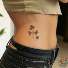 a woman's stomach with four leaf clover tattoos on her lower back and side