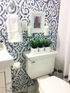 a white toilet sitting next to a sink in a bathroom under a blue and white wall