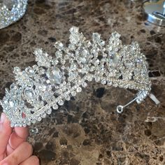 a close up of a person holding a tiara on a table with other items in the background