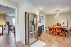 Kitchen remodel with white upper cabinets, a grey backsplash, light granite countertops, new vinyl plank flooring, and farm sink under the bay window Flip House