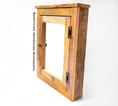 a small wooden cabinet with a mirror on the front and bottom panel, attached to a white wall