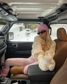 a woman sitting in the back seat of a car wearing pink socks and a knitted hat