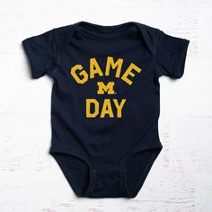 Super soft 100% cotton baby onesie.Designed in Michigan by The Mitten State.Assembled in USA.Officially licensed by the University of Michigan. Casual Onesie With Letter Print For Game Day, Cotton Bodysuit With Letter Print For Playtime, Cotton Onesie With Letter Print For Playtime, Father's Day Cotton Onesie With Graphic Print, Cotton Onesie For Father's Day, Family Matching Onesie With Graphic Print For Playtime, Cotton Onesie With Graphic Print For Playtime, Cotton Graphic Print Onesie For Playtime, Playtime Cotton Bodysuit With Name Print