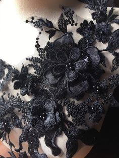 the back of a dress with black flowers and pearls on it's neckline