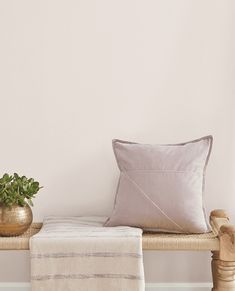 a wooden bench with two pillows and a potted plant