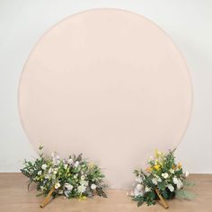 two vases filled with flowers sitting on top of a wooden floor next to a white wall