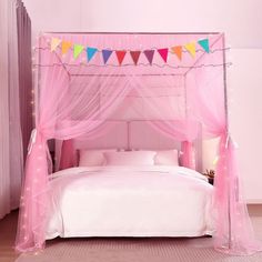 a pink canopy bed with colorful bunting and lights on the headboard, in a bedroom