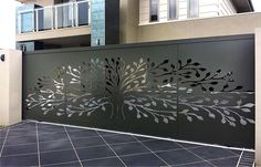 a large metal gate with leaves and flowers on the outside, in front of a building