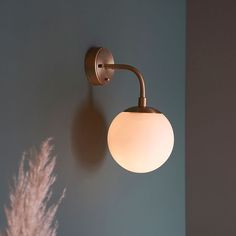 a light that is on the wall next to a vase with some flowers in it