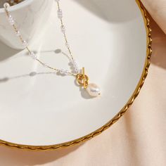 Elevate your look with the Pearl Drop Gold Necklace. The delicate pearl beads add a touch of elegance and sophistication to any outfit. Make a statement and exude confidence with this timeless piece. DETAILS & SIZE Finish: 18K gold plate Materials: Stainless Steel; Synthetic Pearl; Freshwater Pearl (pendant) Measurements: Pendant: 11x7.5mm; Chain: 21" Toggle pendant clasp Waterproof, tarnish-resistant, and nickel free Shop the Pearl Passion collection! Or shop our Necklaces for more options to layer this with! Feminine White Pearl Chain Necklace, Gold Feminine Pearl Pendant Necklace, Feminine Gold Pearl Pendant Necklace, White Pearl Drop Necklace In Feminine Style, Chic Gold Pearl Necklace With Pearl Charm, Feminine White Pearl Necklace With Pearl Drop, Feminine Gold Necklace With Pearl Drop, White Feminine Pearl Drop Necklace, Feminine Gold Necklace With Pearl Charm