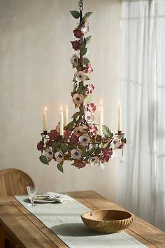 a chandelier with flowers hanging from it's centerpiece in a dining room