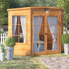 a small wooden shed with curtains on the windows