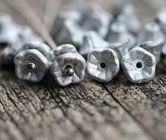 some silver beads are laying on a wooden surface