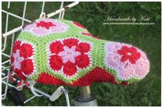 a close up of a bicycle handlebar with a crocheted bag on it