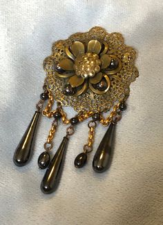 "Hello and Welcome to LiamBySevanna! Prior-purchasing any listing from this shop, please Ask question/s, Request additional photos, to make sure the listed item, is the right choice for you! Per our store policy we don't accept returns Listing is for;  Art Deco Floral Festoon Brooch Pin W/Enamel marcasite Genuine Hematite Stones ~ pin mechanism functions properly safe & secure ~ Brooch Center is a 3 dimensional Flower with hematite orbs & enamel petals ~ large Marcasite Stones at center ~ bottom festoon drapes are chained to matching larger drops and orbs ~ Brooch measures 4  inch drop length, by 2 inch wide ~ weights 33.2 grams ~ Hematite's are non-magnetic, natural stones ~ beautiful larger Art Deco brooch.  Reminder: You can \"always\" prevent any wrong purchase/s by Communicating, Inqu Traditional Evening Jewelry Brooch, Traditional Evening Brooch Jewelry, Victorian Handmade Pendant Brooches, Enamel Brooch Jewelry For Evening, Antique Clip-on Brooch Gift, Antique Clip-on Brooches As Gifts, Antique Clip-on Brooches For Gifts, Antique Clip-on Brooches As A Gift, Ornate Bronze Brooch Jewelry