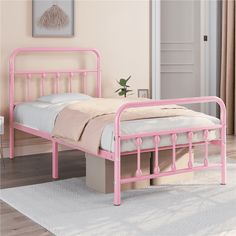 a pink metal bed frame sitting on top of a wooden floor next to a white rug