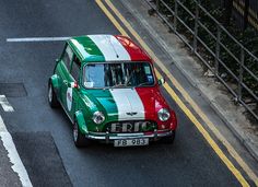 an old green and white car driving down the street