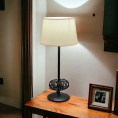 a lamp sitting on top of a wooden table next to a framed photo and an empty picture frame