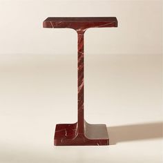 a red marbled object stands upright on a white surface