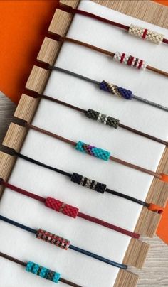 several different types of bracelets are displayed on a wooden stand with an orange wall in the background