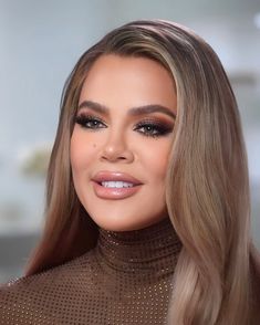 a woman with long blonde hair wearing a brown turtle neck sweater and gold eye makeup