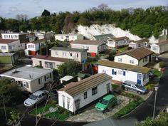 an aerial view of houses in a residential area with cars parked on the street and cliffs in the background