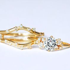 two gold rings with diamonds on them sitting next to each other in front of a white background