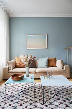 a living room filled with furniture and a large painting on the wall above it's coffee table