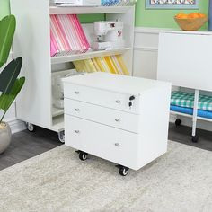 a white cabinet sitting next to a green wall in a room with a rug on the floor