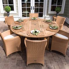 an outdoor dining table set with place settings on the outside patio, next to potted plants