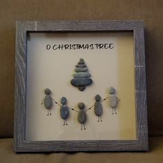 there is a framed picture with rocks in the shape of birds and a christmas tree