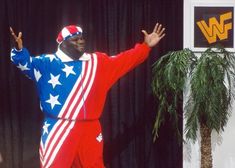 a man dressed in an american flag outfit standing on stage with his arms outstretched and hands out