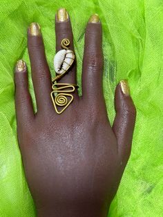 These beautiful Cowry shell rings are handmade in Kenya. Material: brass and cowry shell Genuine Cowry Brass and off white color: Adjustable: Yes Style: Boho & hippie Please note that based on the nature of the material and the way is made the cowries position might differ. Adjustable Cowrie Shell Beachy Jewelry, Traditional Cowrie Shell Jewelry, Handmade Brown Cowrie Shell Jewelry, Cowrie Shell-shaped Jewelry For Beach Season, Shell Rings, Bohemian Jewelry With Shell-shaped Cowrie Shell, Ocean Ring, Brass Shell, Cowry Shell